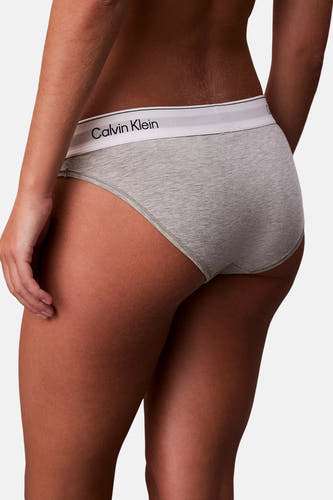 Grijze dames slip van Calvin Klein, met een witte elastische band met logo, van achteren gezien.

