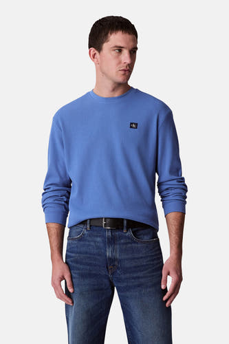 T-shirt bleu à manches longues de Calvin Klein, avec un effet côtelé et un petit logo sur la poitrine.
