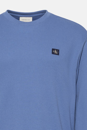T-shirt bleu à manches longues de Calvin Klein Jeans, avec une texture à carreaux et un patch logo carré sur la poitrine.