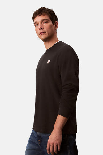 T-shirt noir à manches longues de Calvin Klein, avec une texture tissée et un col visible.
