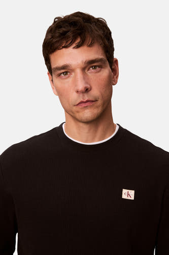 T-shirt noir à manches longues de Calvin Klein, avec un logo subtil sur la poitrine.