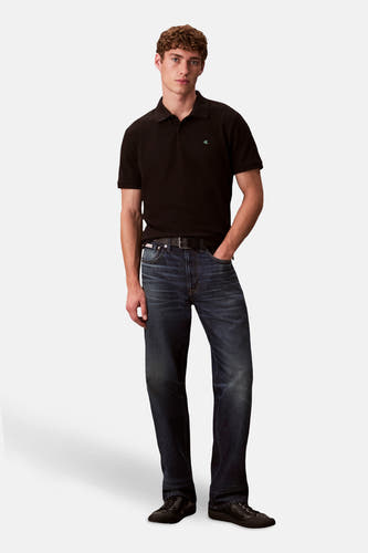 Zwarte polo met korte mouwen van Calvin Klein, gedragen met jeans en een riem.
