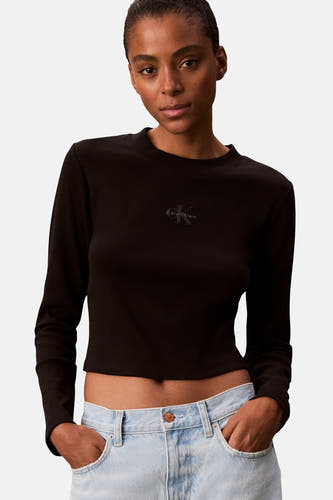 T-shirt noir à manches longues de Calvin Klein, texture côtelée, modèle cropé, associé à un jean bleu clair.