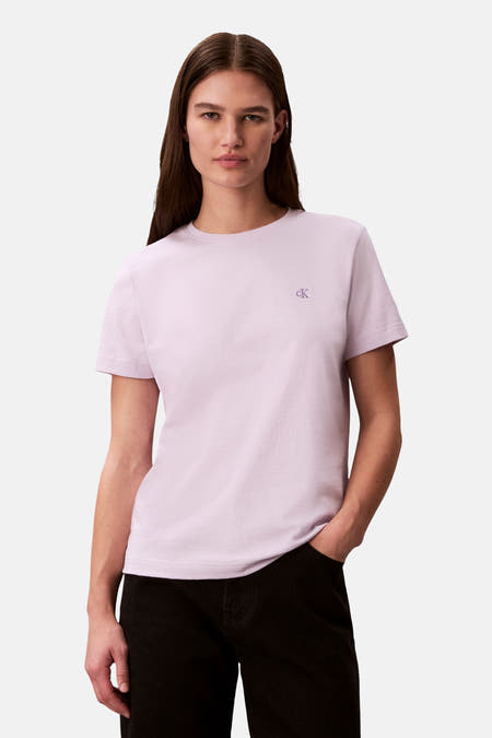 Paars T-shirt met korte mouwen van Calvin Klein, effen voorzijde met logo op de borst, gedragen met een zwarte broek.
