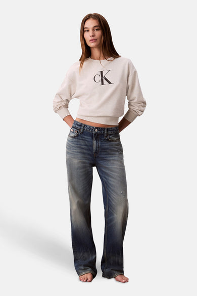 Vrouw in Calvin Klein trui en jeans, staand.