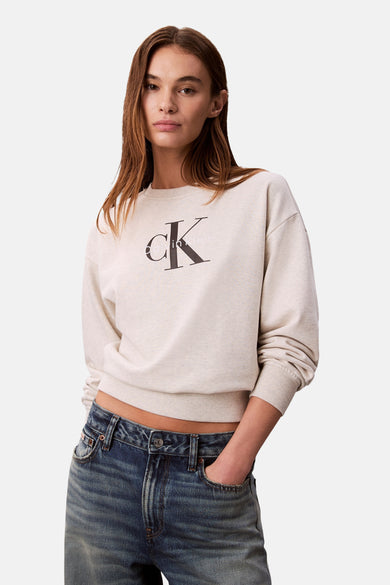 Vrouw in beige Calvin Klein sweater en spijkerbroek.