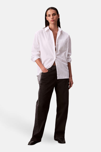 Wit overhemd met lange mouwen van Calvin Klein, gedragen met zwarte jeans en donkere schoenen.
