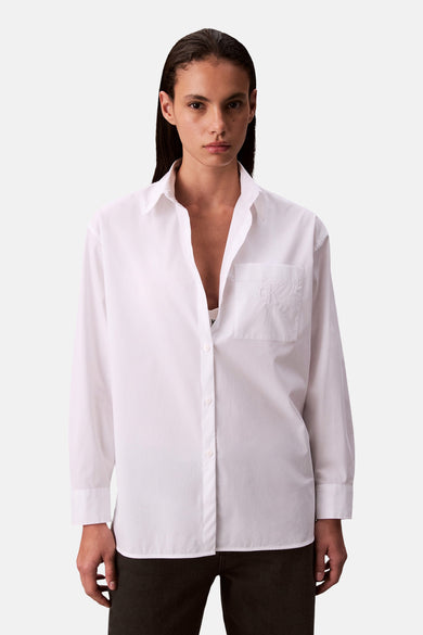 Wit hemd met lange mouwen van Calvin Klein, met borstzakje en gedragen met een witte top.
