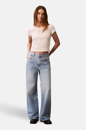 T-shirt écru à manches courtes de Calvin Klein, porté avec un jean ample et des chaussures noires.