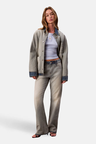 Vrouw in denim jack en broek, staand, lichte tinten.