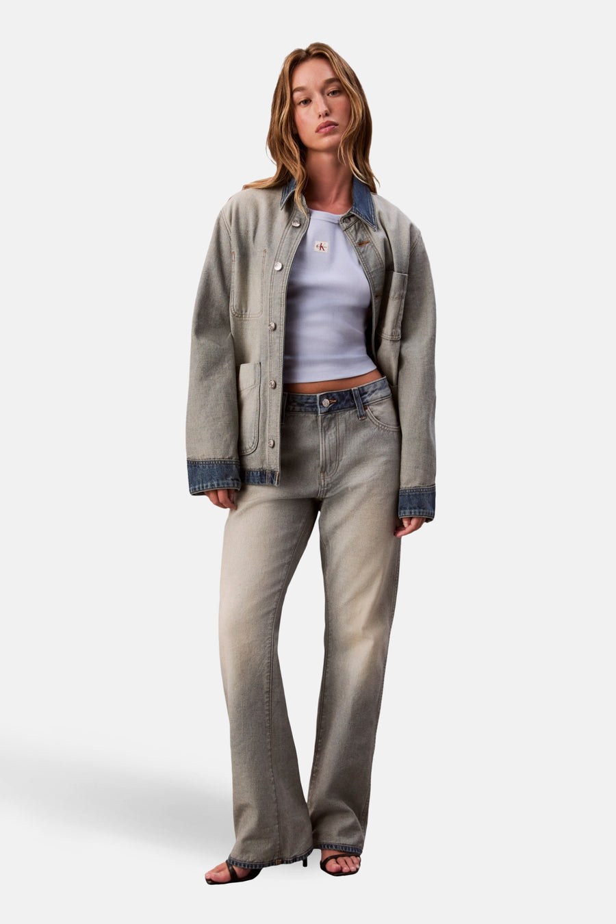 Vrouw in denim jack en broek, staand, lichte tinten.