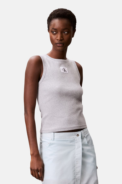 Grijs mouwloos hemd van Calvin Klein, met een subtiele ribstructuur en gedragen met een lichtblauwe rok.
