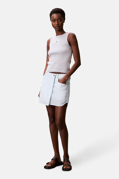 Grijs mouwloos hemd van Calvin Klein, gedragen met een lichtblauwe rok en zwarte sandalen.