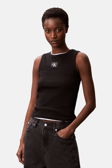 Zwarte singlet van Calvin Klein, met ribtextuur en een logo op de borst, gedragen met een donkere spijkerbroek.
