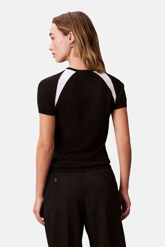 T-shirt noir à manches courtes de Calvin Klein, avec des détails en rayures blanches sur les épaules, associé à un pantalon noir.