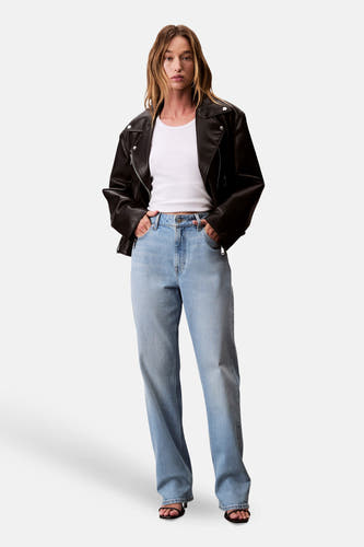 Straight jeans van lichtblauw denim van Calvin Klein, gedragen met een wit shirt en een zwart leren jack.