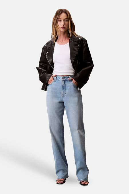 Jean droit en denim bleu clair de Calvin Klein, porté avec un t-shirt blanc et une veste en cuir noir.