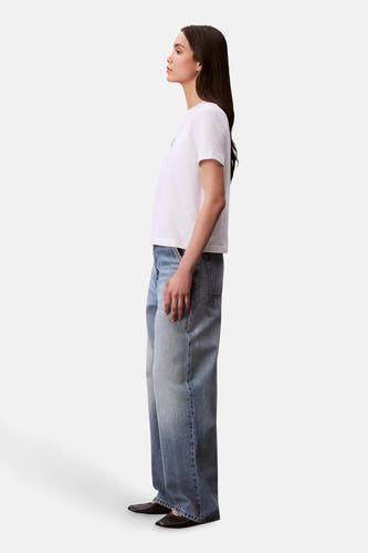 Wit T-shirt met korte mouwen van Calvin Klein, met losvallende jeans en zwarte schoenen, in zij-aanzicht.

