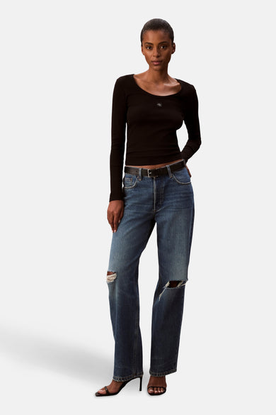 T-shirt noir à manches longues de Calvin Klein, porté avec une ceinture et des jeans déchirés.