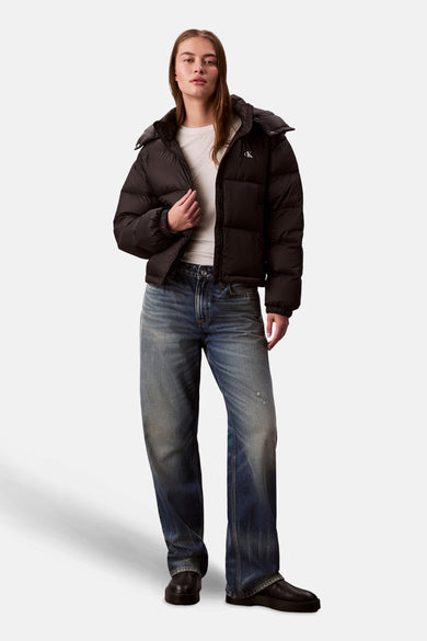 Zwarte korte jas van Calvin Klein, met een witte top en blauwe jeans.
