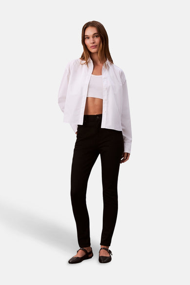 Zwarte skinny jeans van Calvin Klein, gecombineerd met een witte crop top en een losgeknoopt wit overhemd.