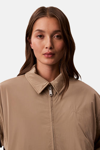 Manteau court beige de Calvin Klein, avec fermeture éclair et logo CK discret.