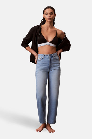 Jean coupe spéciale en denim bleu clair de Calvin Klein, avec une taille haute et des jambes droites, stylisé avec un sweat à capuche noir et un soutien-gorge noir.