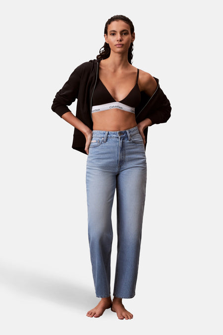 Jeans special fit van lichtblauw denim van Calvin Klein, met een hoge taille en rechte pijpen, gestyled met een zwarte hoodie en zwarte bh.
