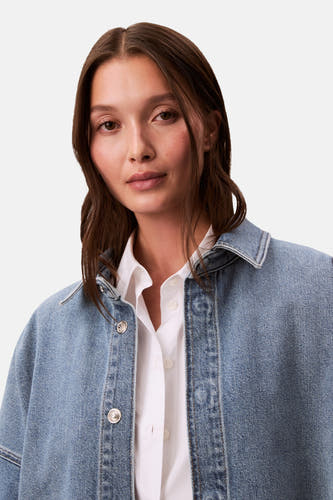 Jeanshemd in middenblauw denim van Calvin Klein, gedragen over een wit overhemd met knoopsluiting.
