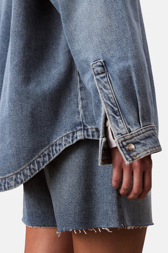 Chemise en denim - bleu moyen de Calvin Klein, avec une longue manche et un bouton argenté.