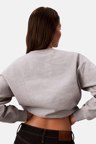 Grijze sweater met ronde hals van Calvin Klein, losjes vallend en gedragen met zwarte jeans.