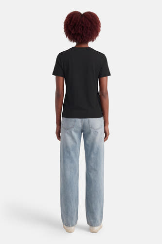 Zwart T-shirt van Calvin Klein, gezien van achteren, gecombineerd met blauwe jeans en witte sneakers.
