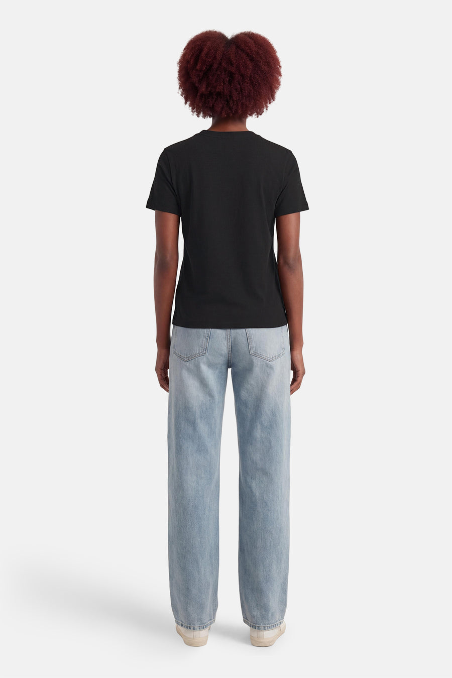 Zwart T-shirt van Calvin Klein, gezien van achteren, gecombineerd met blauwe jeans en witte sneakers.
