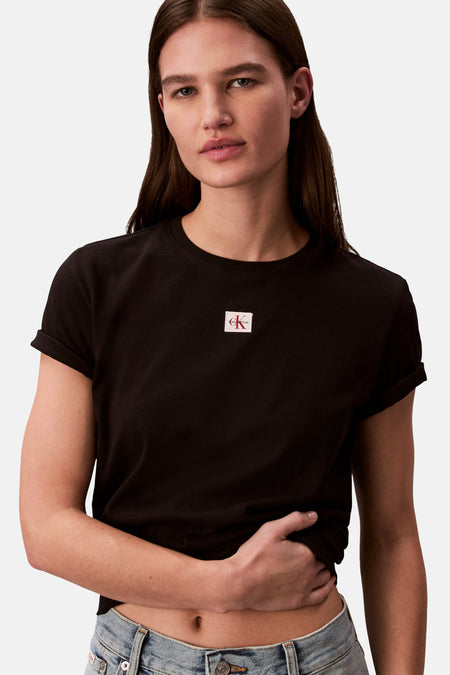 T-shirt noir Calvin Klein, à manches courtes et ourlets retroussés, porté avec un jean.