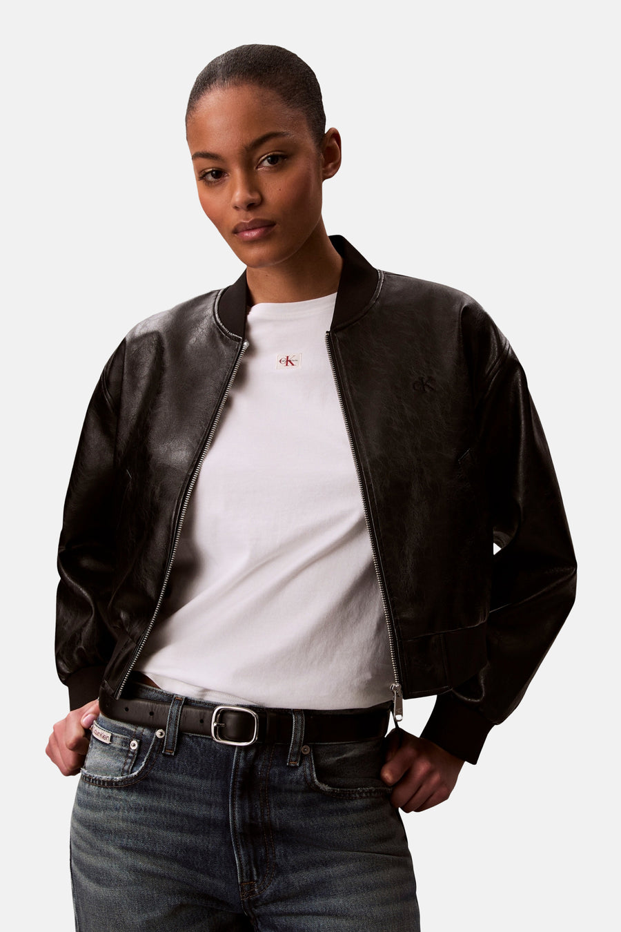Wit T-shirt van Calvin Klein, gedragen onder een zwart leren bomberjack met een zilveren ritssluiting.