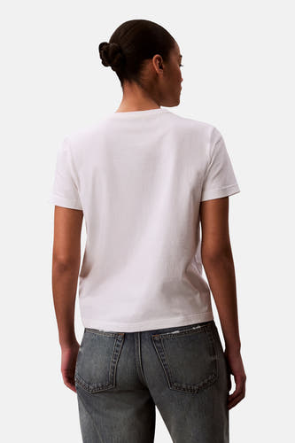 Wit T-shirt van Calvin Klein, gezien van achteren, met korte mouwen en gecombineerd met een blauwe jeans.
