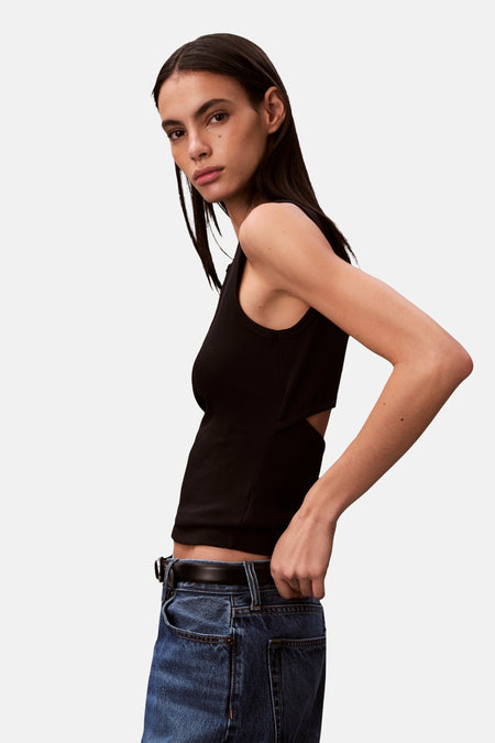 Haut noire Calvin Klein avec un détail ouvert sur le côté, portée avec un jean bleu et une ceinture.