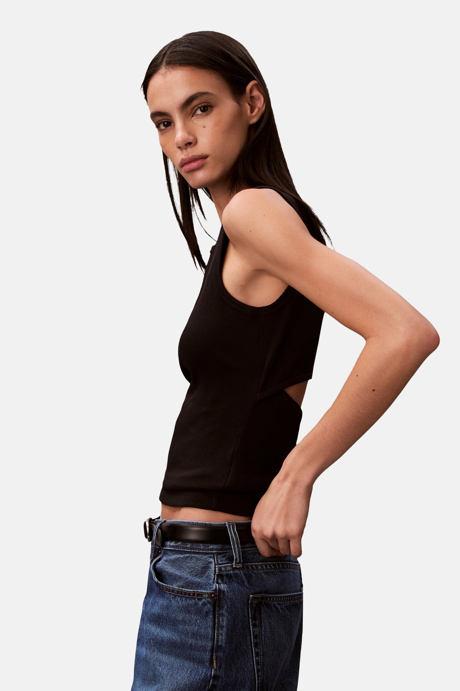 Haut noire Calvin Klein avec un détail ouvert sur le côté, portée avec un jean bleu et une ceinture.