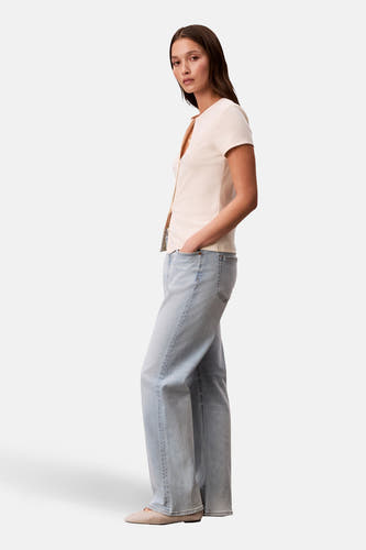 Gilet écru de Calvin Klein, avec fermeture à boutons, porté avec un jean bleu clair et des chaussures plates.