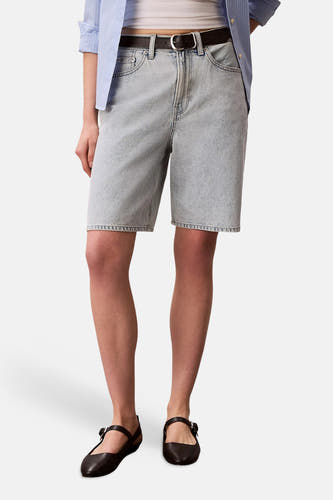 Short en jean bleu clair Calvin Klein, porté avec une chemise rayée et des ballerines noires en vue de côté.