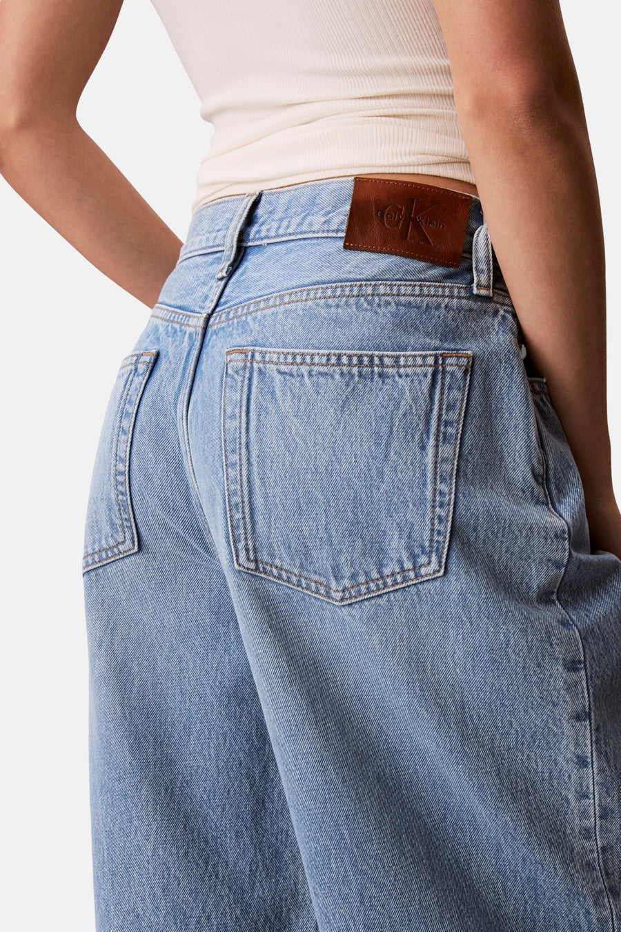Lichtblauwe denim jeans van Calvin Klein met bruin leren logo patch, achterzakken en een lichte ribtop.