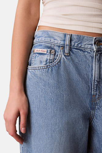 Lichtblauwe denim jeans van Calvin Klein, met merklabel op het muntzakje en een geribbelde crèmekleurige top.
