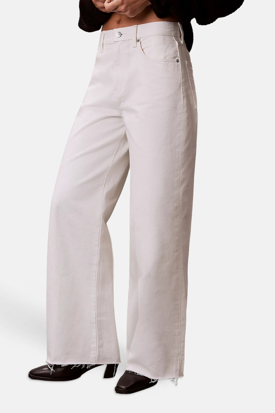Wijde jeans van off-white denim van Calvin Klein, met rafelige zomen en metalen details, gedragen met donkere schoenen.