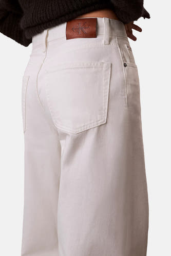 Witte wide-leg jeans van off-white denim van Calvin Klein, met bruine leren logopatch en opgestikte achterzakken.
