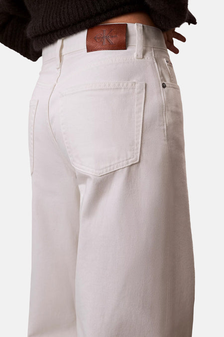 Witte wide-leg jeans van off-white denim van Calvin Klein, met bruine leren logopatch en opgestikte achterzakken.