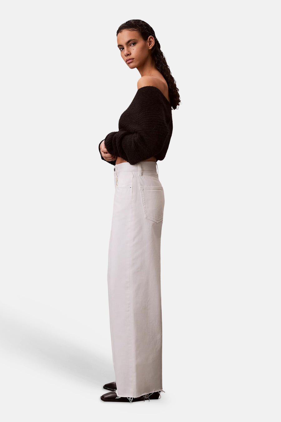Gebroken witte wide-leg jeans van denim van Calvin Klein met onafgewerkte zoom, gedragen door een model in zijprofiel.