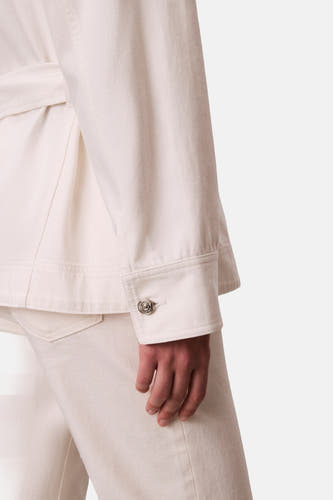 Veste courte en denim blanc cassé de Calvin Klein, avec détail de bouton argenté sur la manche, courte.