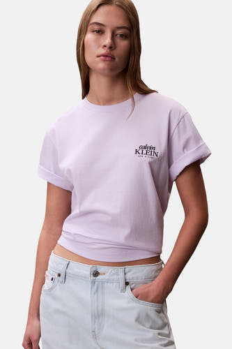Paars T-shirt met korte mouwen van Calvin Klein, met opgerolde mouwen en een lichtblauwe jeans.
