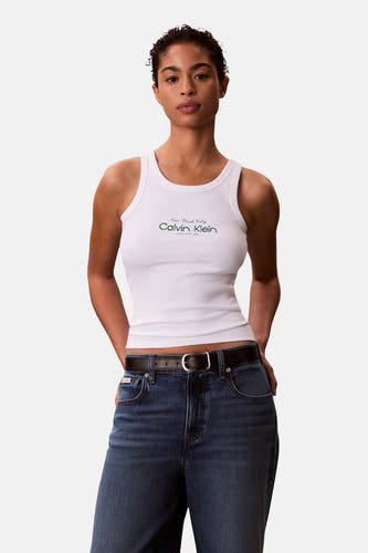 Witte tanktop van Calvin Klein, met logo-opdruk, gecombineerd met een donkerblauwe jeans en een zwarte leren riem.