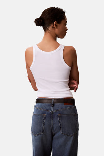 Witte top van Calvin Klein, gezien van achteren met een ribgebreide textuur en gecombineerd met een jeans en riem.